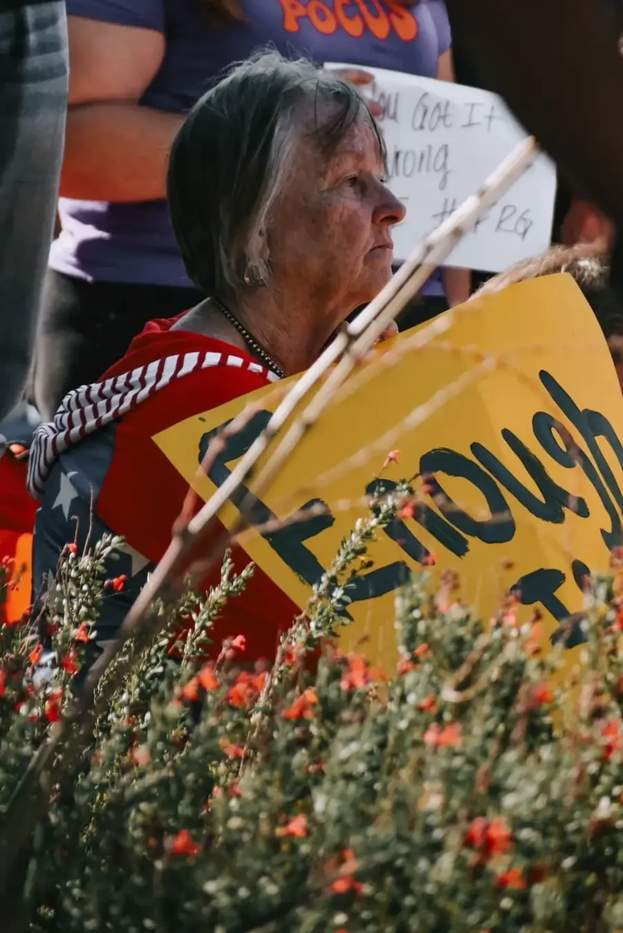 Older attendee holding a yellow sign at a Grand Jury Justice gathering