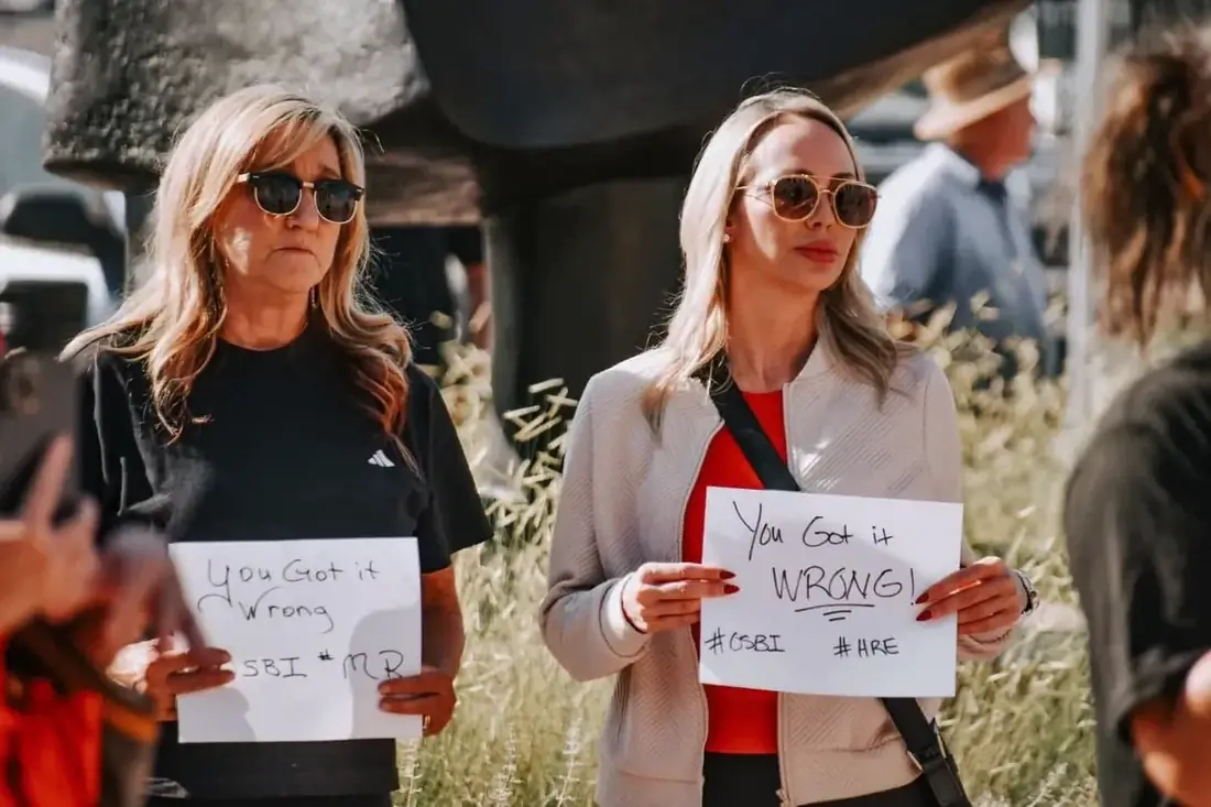 Two attendees holding handwritten signs at a Grand Jury Justice event