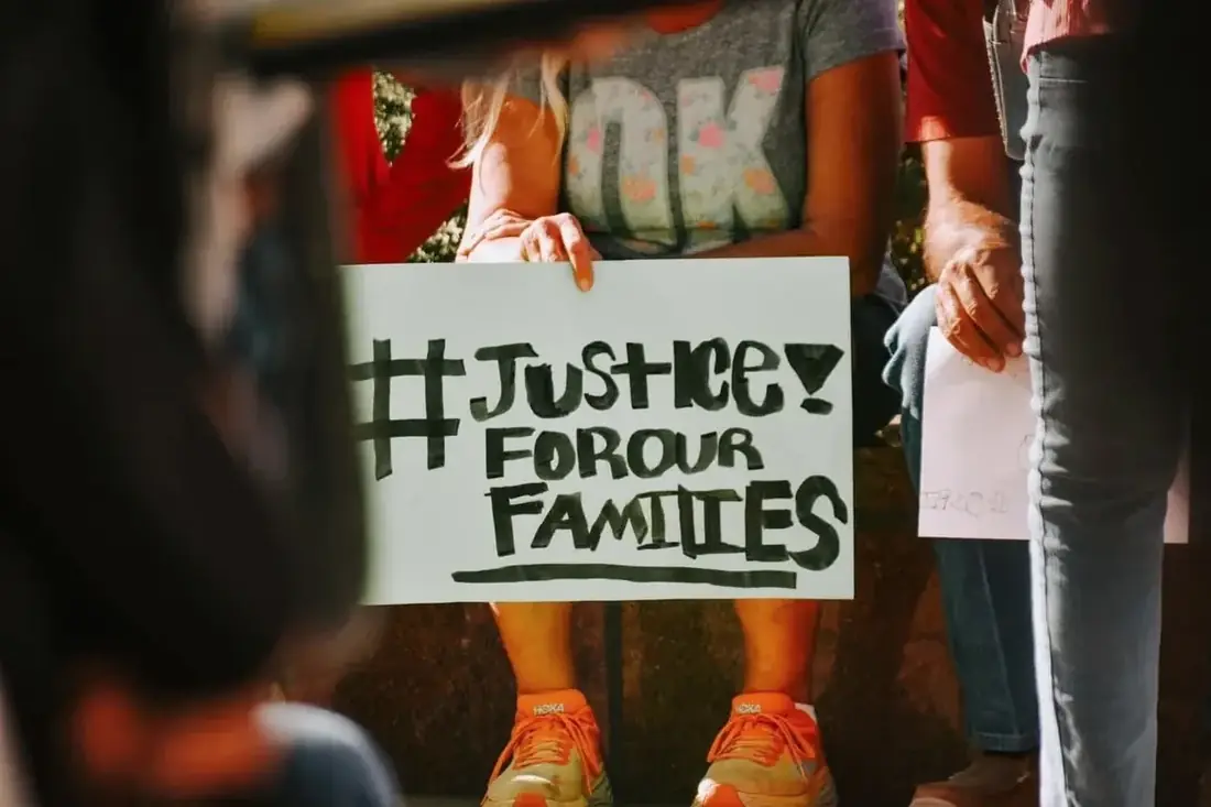 An attendee holds a handmade sign reading Justice for Our Families